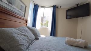 a bedroom with a bed with a television on the wall at Depto en condo, 1D 1B, aire estacionamiento, full in Curicó