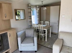 Una cocina y un comedor con mesa y sillas. en Caravan With Front Decking At Coopers Beach Holiday Park Ref 49080Pa, en East Mersea