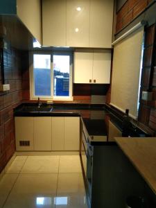 a kitchen with white cabinets and a sink and two windows at Rustic Roots Inn in Jāmb