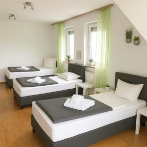 3 Betten in einem Zimmer mit grünen Vorhängen in der Unterkunft SUNNYHOME Monteurwohnungen und Apartments nahe Regensburg in Nittendorf