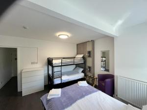 アバーデアにあるDare Valley Accommodation and Campsiteのベッドルーム1室(二段ベッド2台、紫色の椅子付)