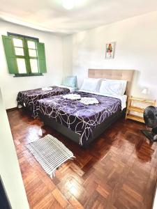a bedroom with two beds and a wooden floor at Casa Charmosa no Centro Histórico in Ouro Preto +42 photos
