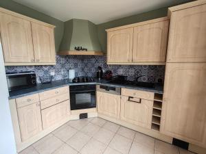a kitchen with wooden cabinets and black counter tops at Gîte De L 'entre 2 Côtes in Vindefontaine +12 photos