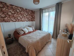 a bedroom with a bed and a stone wall at Gîte De L 'entre 2 Côtes in Vindefontaine