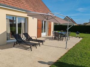 a patio with a table and chairs under an umbrella at Gîte De L 'entre 2 Côtes in Vindefontaine
