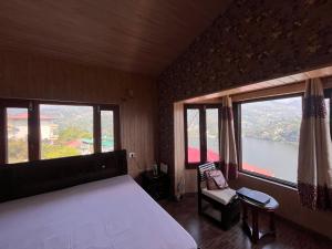 1 dormitorio con 1 cama grande y 2 ventanas grandes en RaahgirStays The Lake Nest, en Bhimtal