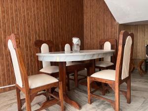 mesa de comedor con sillas y mesa blanca en RaahgirStays The Lake Nest, en Bhimtal