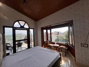 Un dormitorio con una cama grande y una ventana grande en RaahgirStays The Lake Nest, en Bhimtal