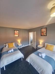 two beds in a room with two tables and two lamps at Bright & cosy 3-bed semi in Wheatley, Doncaster in Arksey
