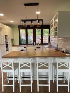 a kitchen with a large kitchen island with white stools at Villa Pastora in Garganta de los Montes