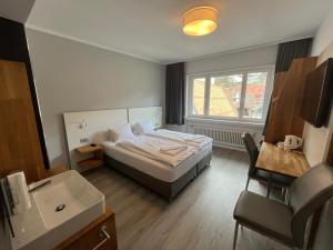 a bedroom with a bed and a sink and a window at Hotel Drei Könige in Chur