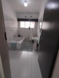 a bathroom with a tub and a toilet and a sink at Khaya guesthouse in Rustenburg