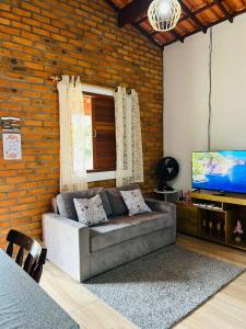 een woonkamer met een bank en een flatscreen-tv bij Chalé Quartzo no Recanto Diamantina entre Palmeiras e Capão in Palmeiras