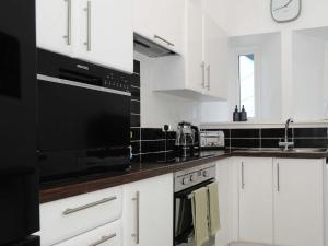a kitchen with white cabinets and black appliances at Wanderers Rest in Lynton +15 photos