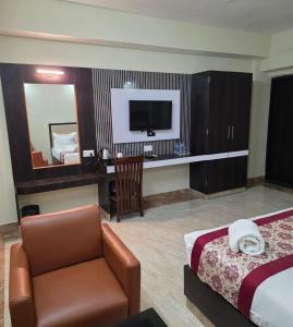 a hotel room with a bed and a chair and a television at Hotel Star Bodh Gaya in Bodh Gaya
