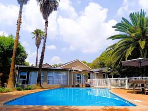 a house with a swimming pool and palm trees at Joy Haven - Cottage in Centurion