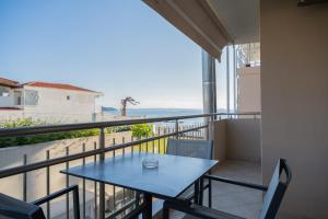 a balcony with a blue table and a view of the ocean at Meliton Inn Hotel & Suites by the beach in Neos Marmaras