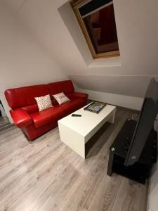 a living room with a red couch and a coffee table at Appartement confortable avec piscine à Cour-Cheverny in Cour-Cheverny