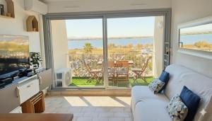 a living room with a couch and a large window at Le Moderna 1 ère ligne Bord de Mer Palavas in Palavas-les-Flots