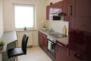a kitchen with red cabinets and a black chair in it at SUNNYHOME Monteurwohnungen und Apartments nahe Regensburg in Nittendorf