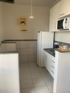 a kitchen with a white refrigerator and a microwave at Kit Dom José in Araxá
