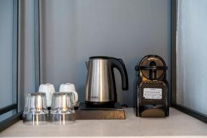 a tea kettle and four cups on a counter at Meliton Inn Hotel & Suites by the beach in Neos Marmaras