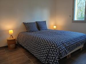 ein Schlafzimmer mit einem Bett mit einer blauen Bettdecke und zwei Lampen in der Unterkunft Logement insolite avec Jeux et Jacuzzi in Soulosse-sous-Saint-Élophe