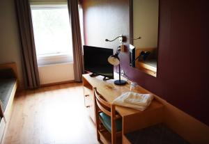 a room with a desk with a lamp and a mirror at Åsele Wärdshus in Åsele