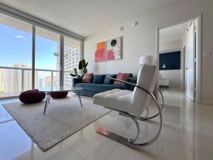 sala de estar con silla blanca y sofá azul en Stylish 1B Icon Brickell 25th fl Pool Spa Gym Parking, en Miami