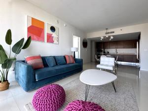 Una sala de estar con un sofá azul y una mesa. en Stylish 1B Icon Brickell 25th fl Pool Spa Gym Parking, en Miami