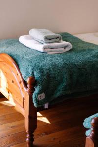a bed with a green blanket and towels on it at Henllys Estate B and B in Llandovery
