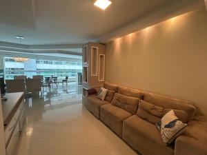a living room with a couch and a dining room at Apto Almeida e Moraes 3 Suítes com churrasqueira Meia Praia in Meia Praia