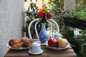 una mesa con dos platos de fruta y un jarrón con flores en Amarcorde Home in Corso Buenos Aires con 6 posti letto, en Chiavari