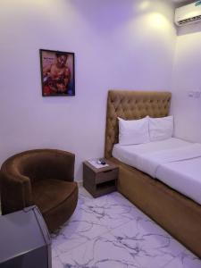 Un pequeño dormitorio con una cama y una silla. en Danamic view hotel, en Abuja
