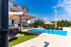 a swimming pool with an umbrella and a house at Apartment Kampor 4 in Kampor
