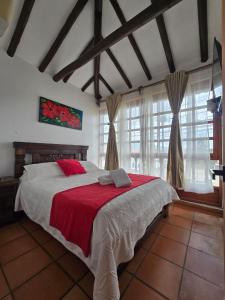 a bedroom with a large bed with a red blanket at Aparta Hotel El Refugio de María in Villa de Leyva