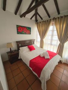 a bedroom with a large bed with a red blanket at Aparta Hotel El Refugio de María in Villa de Leyva +31 photos