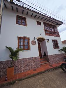 a white house with a palm tree in front of it at Aparta Hotel El Refugio de María in Villa de Leyva