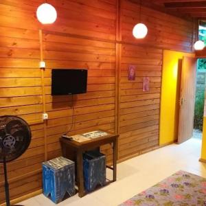 um quarto com uma parede de madeira, uma televisão e uma mesa em Cabanas de Marina em Imbituba