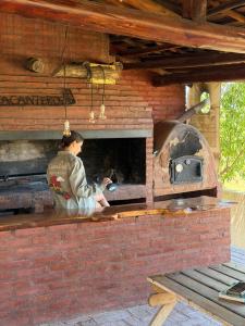 Eine Frau kocht in einem Steinofen. in der Unterkunft El Alma De Yacanto Hotel Boutique in Villa Yacanto