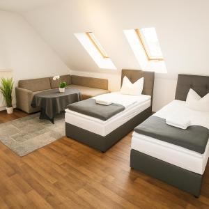 zwei Betten und eine Couch in einem Zimmer mit Dachfenstern in der Unterkunft SUNNYHOME Monteurwohnungen und Apartments in Schwandorf in Schwandorf in Bayern
