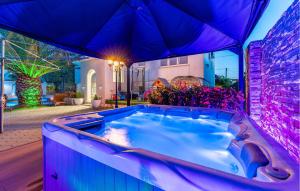 a hot tub in a backyard with an umbrella at Beautiful Apartment In Sukosan in Sukošan