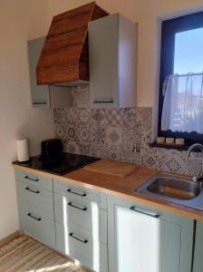 a kitchen with white cabinets and a sink and a window at Domek Zgredek in Żywiec +19 photos