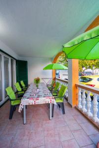 una mesa y sillas en un balcón con sombrillas verdes en Apartmani-Finka, en Vodice