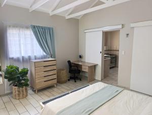a bedroom with a bed and a desk and a table at Joy Haven - Cottage in Centurion