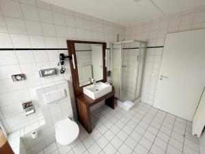 ein Badezimmer mit Waschbecken, Toilette und Spiegel in der Unterkunft Hotel Casa Nostra in Schloß Holte-Stukenbrock