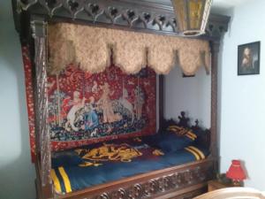 un letto a baldacchino con un dipinto sopra in una camera da letto di Le terrier des sorciers a Crémieu