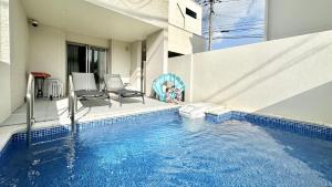 ein Swimmingpool mit zwei Stühlen und einem Haus in der Unterkunft Grandioso Onna 7-D - Vacation STAY 17394v in Atsutabaru