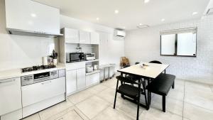 eine Küche mit weißen Schränken und einem Tisch und Stühlen in der Unterkunft Grandioso Onna 7-D - Vacation STAY 17394v in Atsutabaru