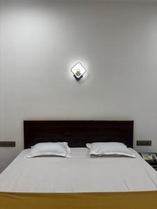 a bed with two pillows and a clock on the wall at Samudra Courtyard in Kashid